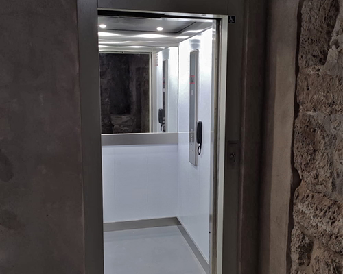 Elevador domestico con un espejo en la mitad de la pared para dar profundidad a la cabina.